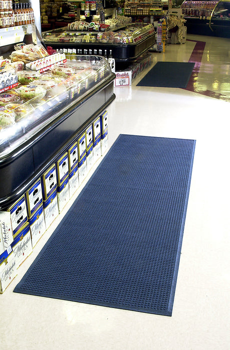 Insitu image of the navy Waterhog Fashion Mat in a retail entrance to help traps dirt and moisture. The Mat Group UK.