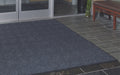 Insitu image of a Navy Waterhog Premier Fashion Mat in an outdoor entranceway leading into a building. The Mat Group UK.