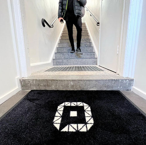 Insitu product image of PrintPlush Logo Mat at the base of stairs in office. The Mat Group UK.